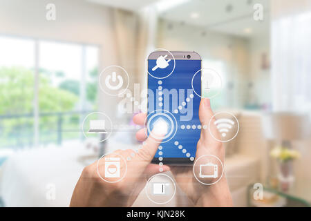 Smart home automation app on mobile with home interior in background. Internet of things concept at home. Smart technology 4.0 Stock Photo