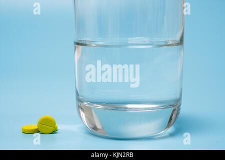 Pills and medication and a glass with water on a blue  background Stock Photo