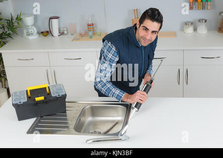plumber using a silicone tube on a sink Stock Photo
