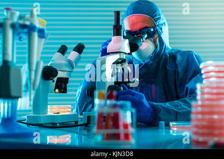 Research Of dangerous viruses in the laboratory. Prevention of a pandemic. A scientist in a biological protective suit works with a pipette Stock Photo