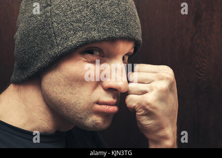 Young aggressive Caucasian man shows fist. Closeup studio face portrait, selective focus Stock Photo