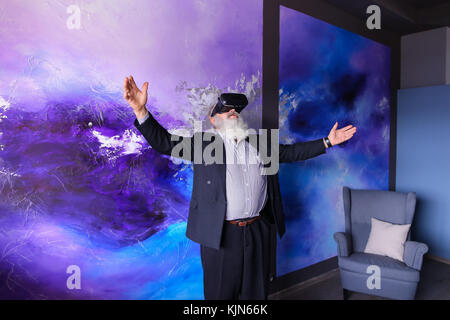 Elderly modern man using VR glasses entertained and hanging out  Stock Photo