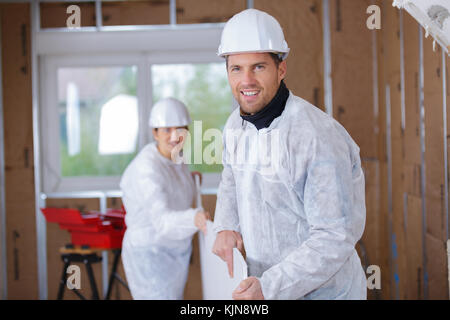 two workers carrying plank at a construction site Stock Photo