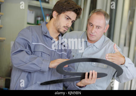 workers holding and discussing shaped object Stock Photo