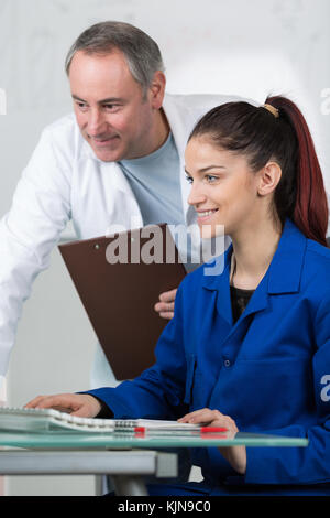 teacher assisting young student in computer room at college Stock Photo