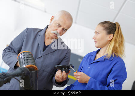 female mechanic and teacher holding car air filter Stock Photo