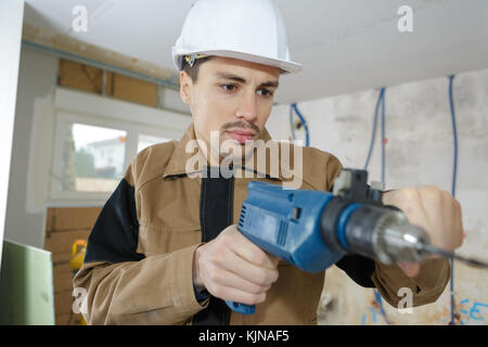 Workman using electric drill Stock Photo