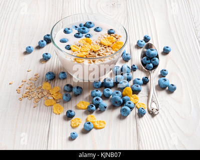 Bowl of homemade yogurt with muesli and fresh blueberry on wooden table. Fresh yogurt. Healthy food concept. High resolution product. Stock Photo