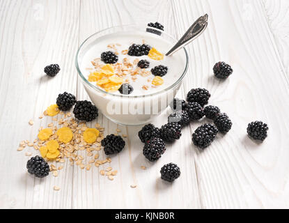 Bowl of homemade yogurt with muesli and fresh blackberry on wooden table. Fresh yogurt. Healthy food concept. High resolution product. Stock Photo