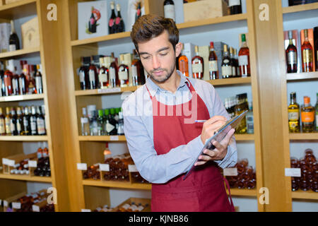 salesman taking inventory in wine store Stock Photo