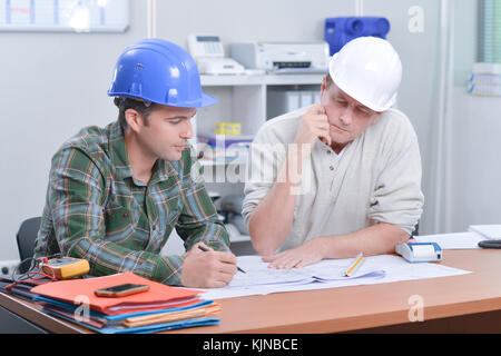 Two men in hardhats looking at blueprints Stock Photo