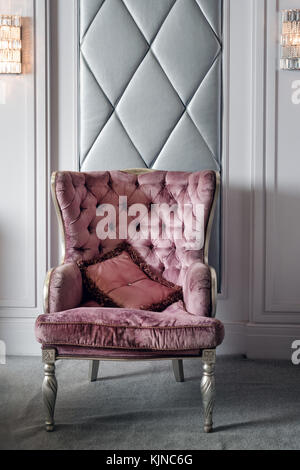 Luxury Interior. Luxurious pink velvet armchair, antique carved furniture, classic interior detail Stock Photo