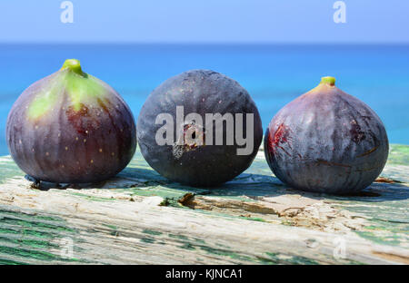 Three blue figs on green grunge wooden background against blue sea bokeh Stock Photo