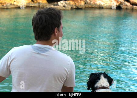 Young man with his dog, looking at the sea Stock Photo