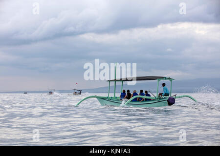 Local fishermen in traditional outriggers with tourists during dolphin watching tour at Lovina Beach, Buleleng Regency on the island Bali, Indonesia Stock Photo