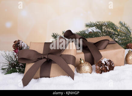 Brown gift boxes with Christmas ornaments on snow with colorful holiday background Stock Photo