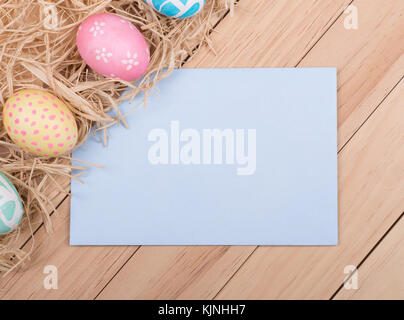 Decorated Easter eggs next to envelope on a wood background Stock Photo