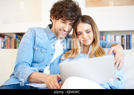 Shot of a lovely young couple relaxing on the couch and using a laptop. Stock Photo