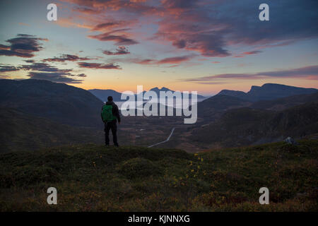 Backpacker looking and a beautiful sunset over the Norwegian fjords Stock Photo