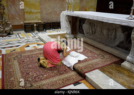 A Catholic woman from India kneels down in prayer over her newborn baby after baptism naming ceremony at the Franciscan Saint Saviour or San Salvador church located in Saint Francis street in the Christian Quarter in the old city East Jerusalem Israel Stock Photo