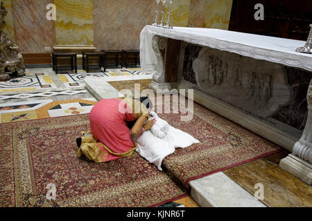 A Catholic woman from India kneels down in prayer over her newborn baby after baptism naming ceremony at the Franciscan Saint Saviour or San Salvador church located in Saint Francis street in the Christian Quarter in the old city East Jerusalem Israel Stock Photo