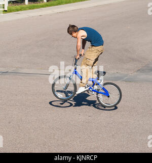 A teenage boy does wheel hops andpeg stands along with other tricks on a BMX bike. Stock Photo