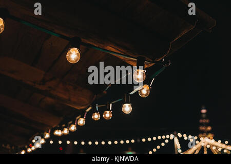 The string of vintage lights bulbs outside at night, lights on the background, selective focus Stock Photo