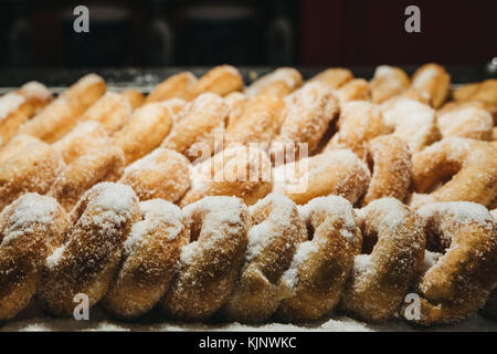 Rows of fresh donuts covered in white sugar on sale at a market small Stock Photo