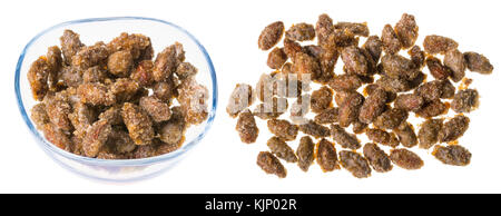 Two piles of freshly roasted almonds in caramel. Sweet candies scattered and in glass bowl. Isolated on white background. Stock Photo