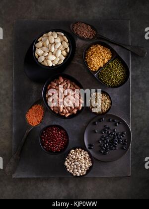 Pulses in bowls against dark background, overhead view. Stock Photo