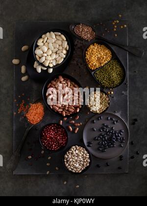 Pulses in bowls against dark background, overhead view. Stock Photo