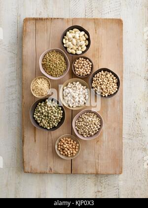 Pulses in bowls on a chopping board, overhead view. Stock Photo