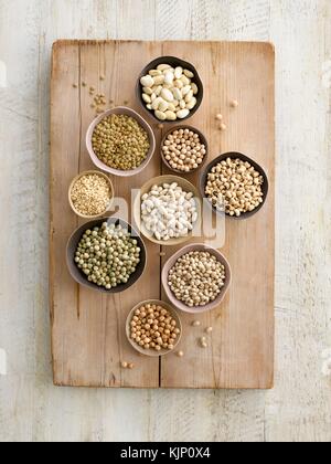 Pulses in bowls on a chopping board, overhead view. Stock Photo