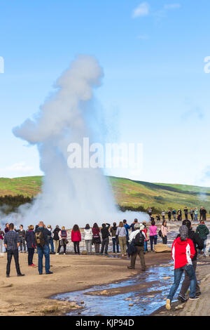 HAUKADALUR, ICELAND - SEPTEMBER 6, 2017: tourists photograph Strokkur geyser in Haukadalur area in september. Haukadalur geyser valley is one of the m Stock Photo