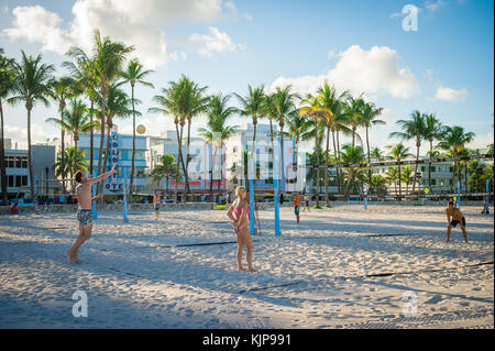 MIAMI - August 31, 2017: Young men and women play beach volleyball on the promenade in Lummus Park against the Art Deco skyline of Ocean Drive. Stock Photo