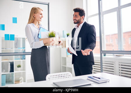 New subordinate looking at hospitable boss welcoming her to take her workplace Stock Photo