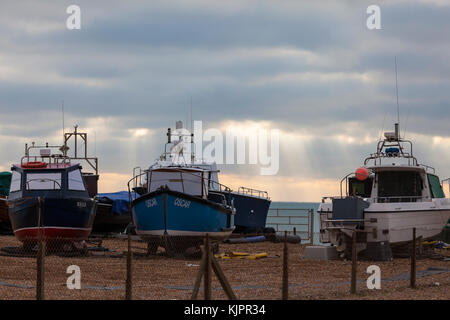 Hastings, East Sussex, UK. 29th November, 2017. Beautiful display of sunlight piercing through the clouds far out to sea whilst several fishing trawler sit on the pebble beach. Photo Credit: Paul Lawrenson /Alamy Live News Stock Photo
