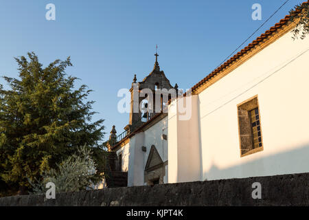 Parish church of Sao Romao with double bells, clock and cross on top of a truncated gable, in Bacal, Braganca, Portugal Stock Photo