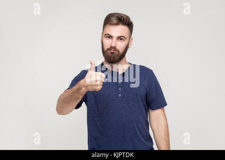 Happy bearded man showing thumb up and smile. Isolated studio shot on gray background Stock Photo
