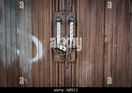 Padlock and chain locked securely on rusty door. Stock Photo