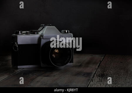 Old retro 35mm camera on a old wooden floor withh dark background with copy space Stock Photo
