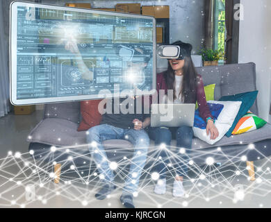 Asian young man and woman in casual clothes wear the virtual reality glasses are watching and showing the technology digital virtual screen via the VR Stock Photo