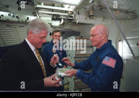 U.S. President Bill Clinton (left) samples space food while visiting NASA STS-95 Space Shuttle Discovery prime crew astronauts Curtis Brown (middle) and John Glenn at the Johnson Space Center April 14, 1998 in Houston, Texas.  (photo by NASA Photo via Planetpix) Stock Photo