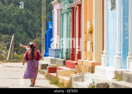 Mayan woman passing at colorful tombs at the cemetery | Chichicastenango | Guatemala Stock Photo