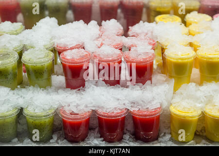 Fresh and healthy kiwi, berry and pineapple fruit juice in closed plastic cups on cold ice Stock Photo