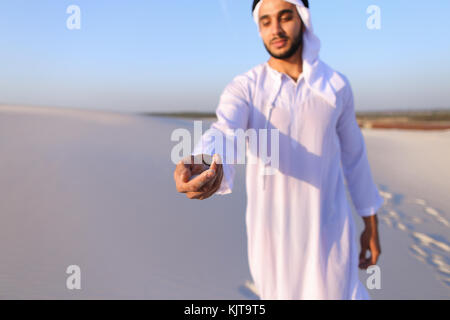 Close-up shot of portrait and hands of young Arab guy in sandy d Stock Photo