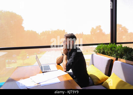 Successful foreman using laptop and documents at cafe. Stock Photo