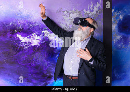 Senior citizen immersed in virtual reality with help of special  Stock Photo