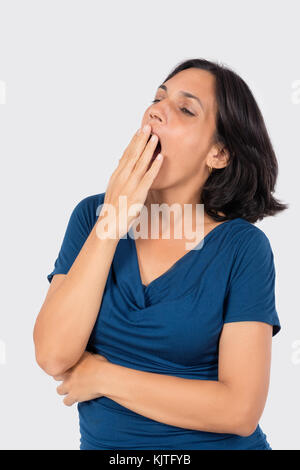 A latin woman yawning, wearing blue blouse and black hair Stock Photo