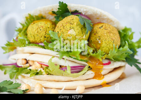 Fresh baked falafel in pita with vegetables, sprouts chickpeas and curry sauce. Vegan Healthy Food Concept. Stock Photo